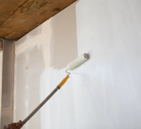 white paint roller painting drywall